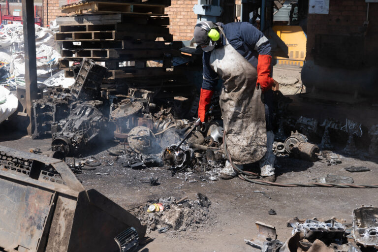A worker in full PPE workign with Scrap Metal